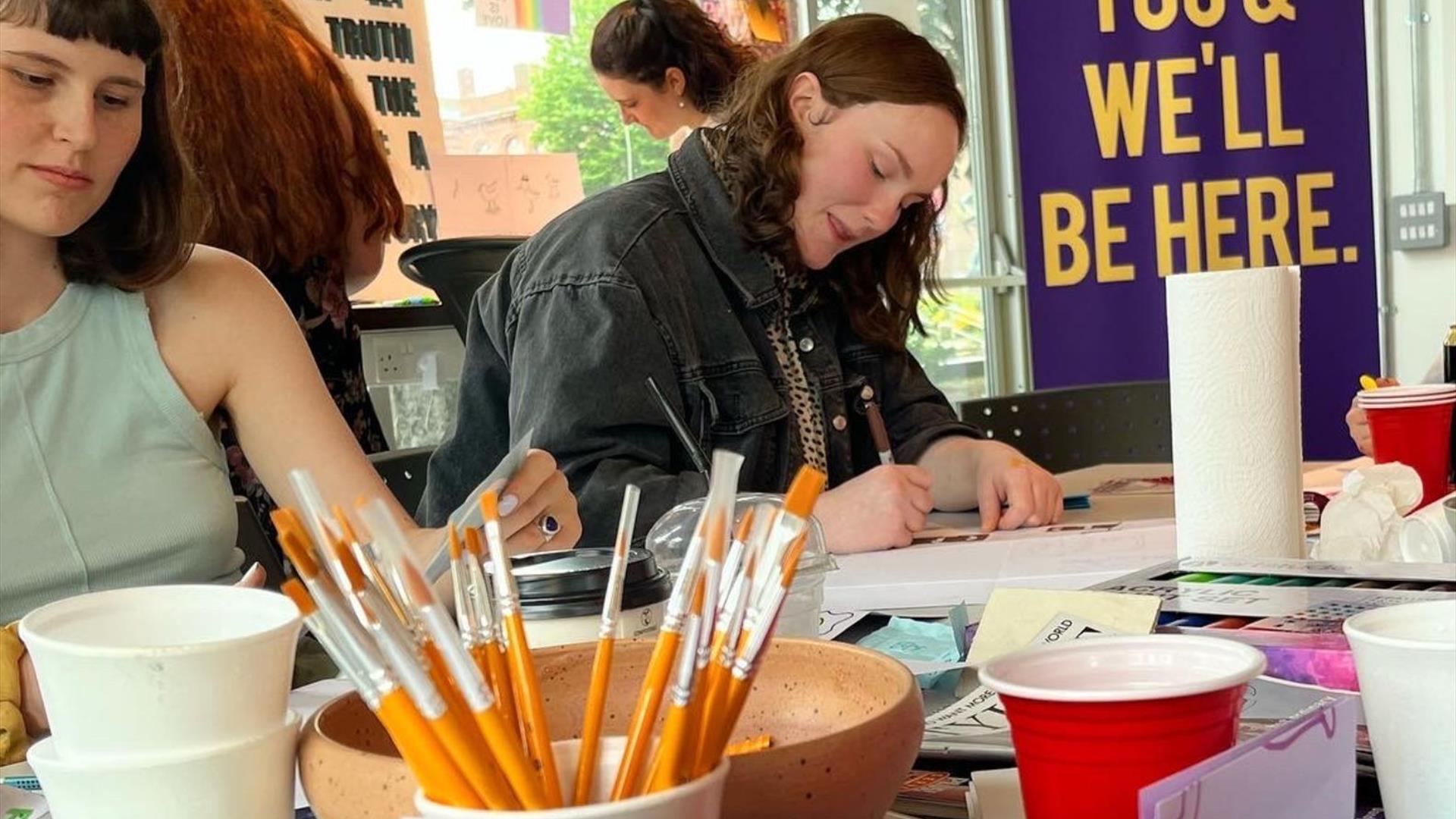 Image of two people taking part in a zine making workshop.