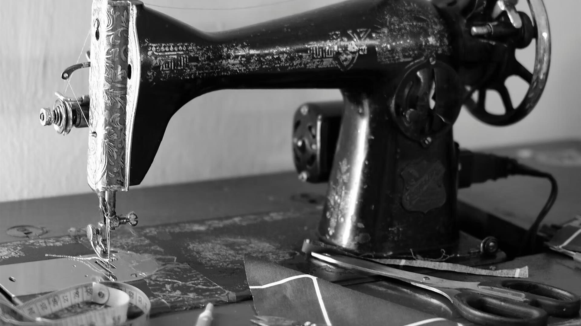 An old fashioned industrial sewing machine which shoes visible signs of rust, wear and patina.