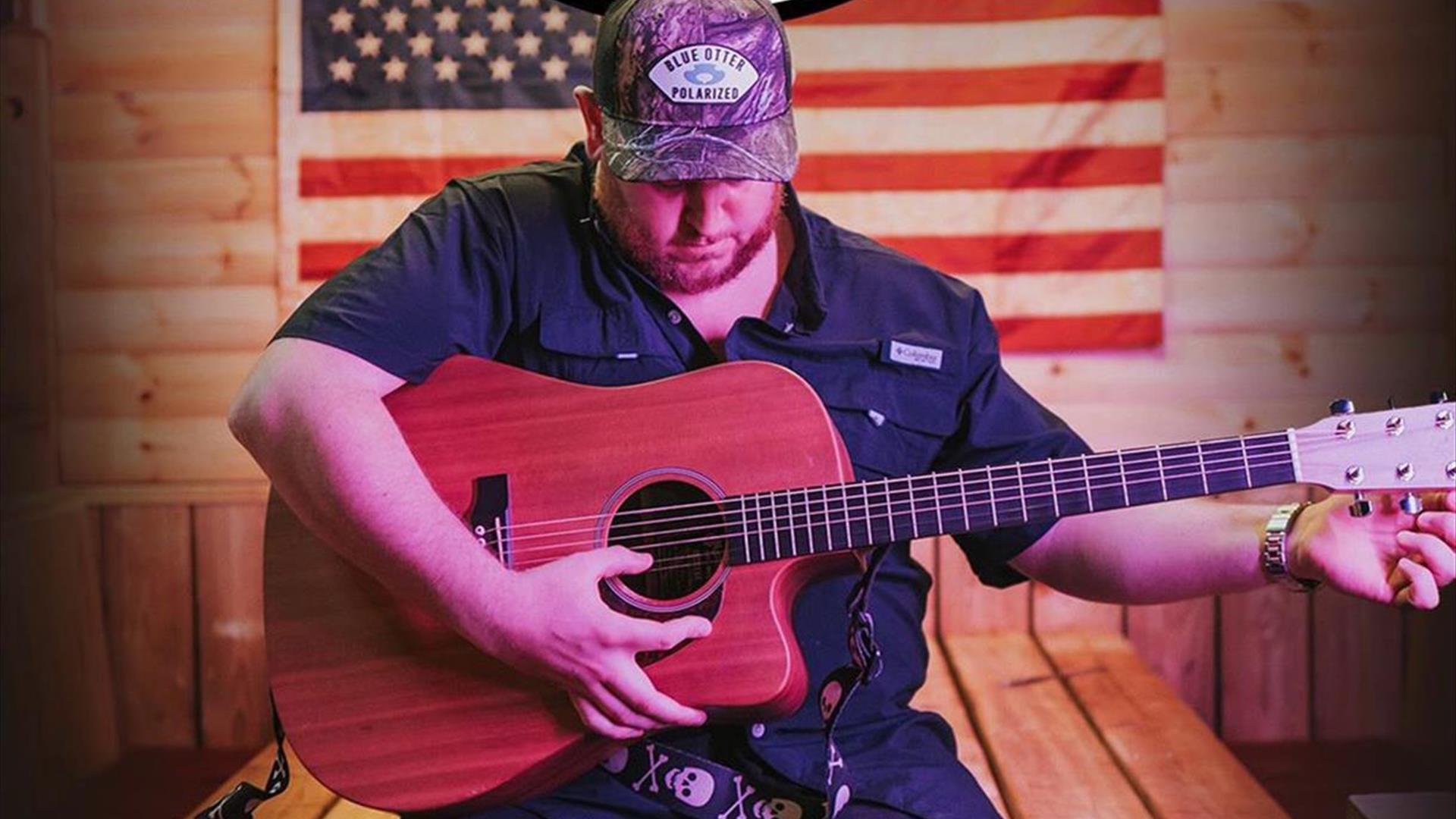 Man strumming guitar in front of American flag