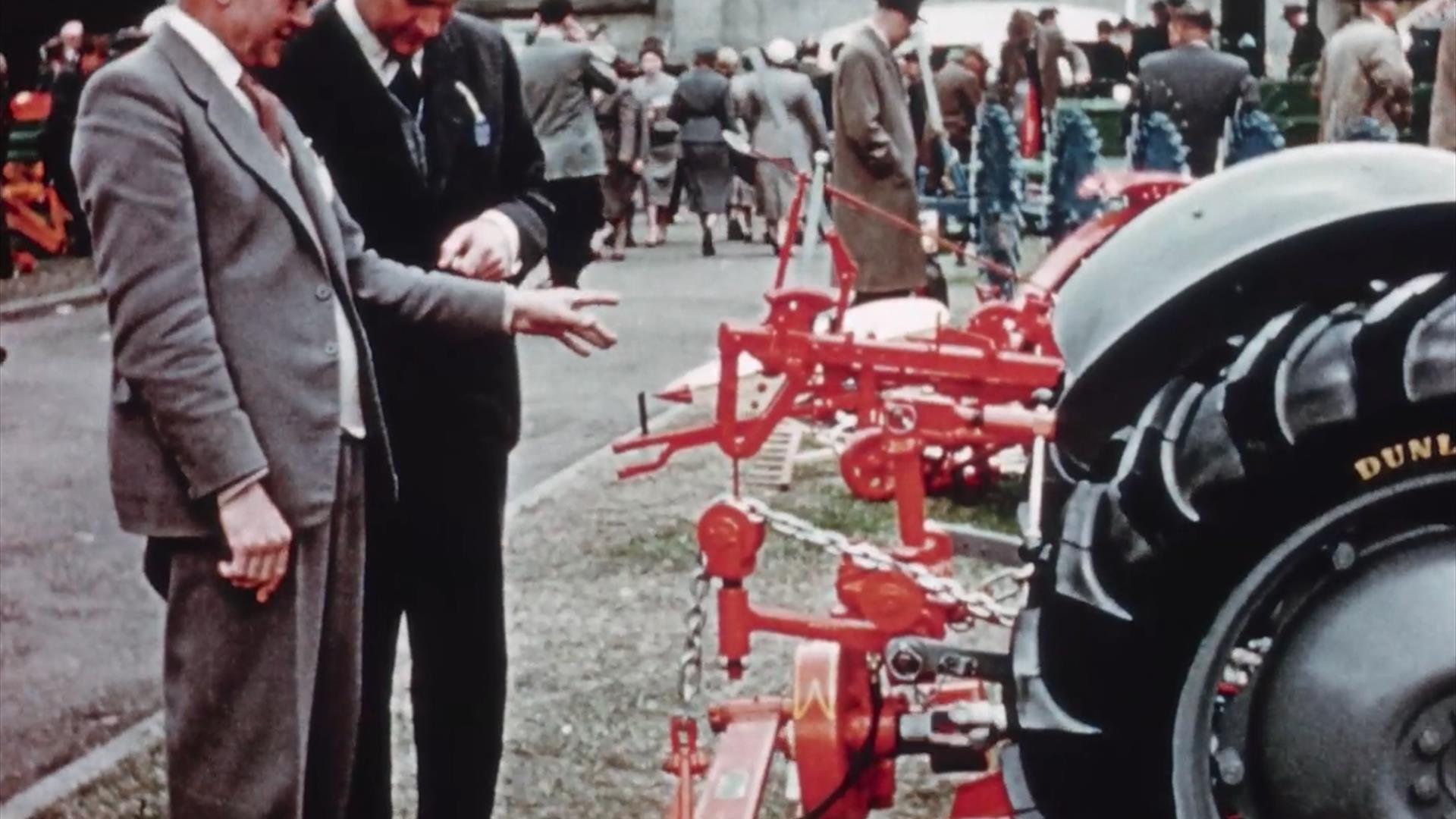 Two judges inspect farm equipment at a fair.