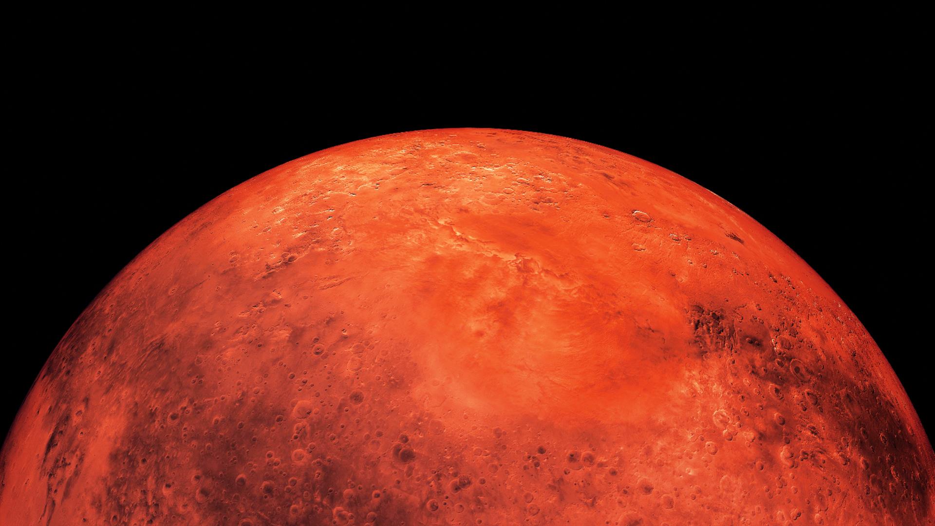 The planet Mars as seen from space, a red sphere surrounded by black.