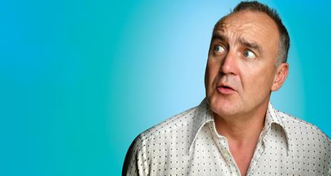 Jimeoin looking to his left side, confused, against a  bold, light blue background.