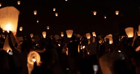 Photograph of floating halloween willow lanterns in the sky at night.
