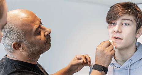 Christian Kotey  painting a teens face