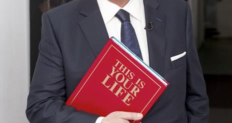 Picture of Eamon Holmes with a red book.