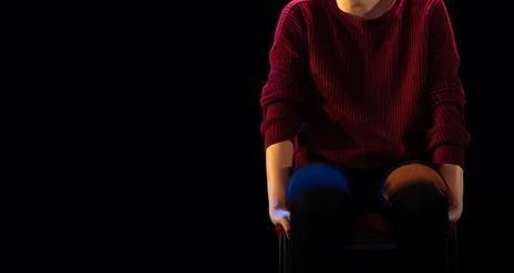 Phoebe Waller-Bridge sits on stool smiling towards audience wearing burgundy jumper and Jeams