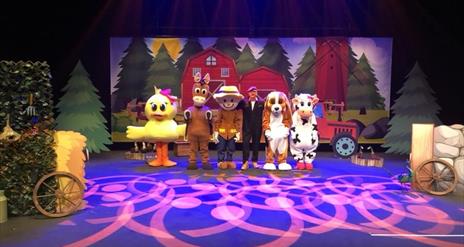 Image shows characters on stage, in front of a farm background