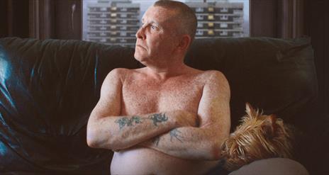 Man with tattoos looking out the window
