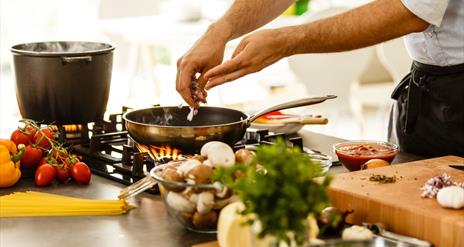 Cook adding ingredients to pan