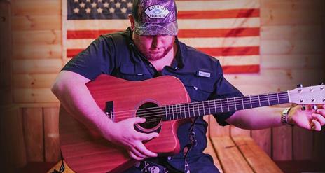 Man strumming guitar in front of American flag