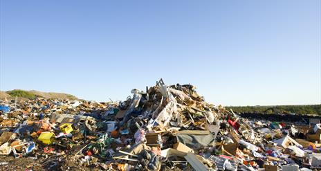 A pile of dumped rubbish with a blue sky