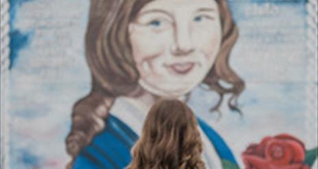 A woman stands before a striking mural of Julie Livingstone, emphasizing the connection between the viewer and the artwork.