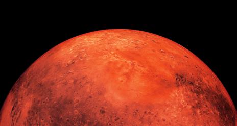 The planet Mars as seen from space, a red sphere surrounded by black.