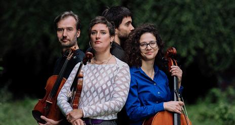 An image of the group posing with their instruments outdoors.