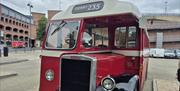 Front view of a vintage Derry City Bus Tours bus with “DERRY 235” displayed above the windscreen, parked in a city centre setting.