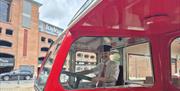 Side view of a vintage Derry City Bus Tours bus with a driver seated in the cab, parked in Derry city centre.