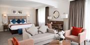 Luxury guestroom boasting a double bed and sitting / living area with blush furnishings