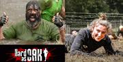 A man in a pool of mud with his thumbs-up and a woman crawling through an obstacle.