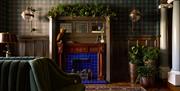 communal lounge area at Portrush Adelphi which features a mahogany fireplace with vibrant blue tiles. The walls are covered with tartan wallpaper and