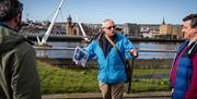 Group listening to guide David from Derrie Danders with the Peace Bridge in the background