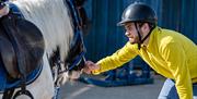 Man stroking a horse's face as part of the Saddle Up by the Sea experience with Crindle Stables