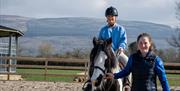 Girl on horseback being led by an instructor as part of the Saddle Up by the Sea experience with Crindle Stables