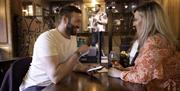 couple seated at table smiling, the male has a smart phone in his hand