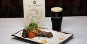 A steak and pint of Guiness beside An Grianan Hotel menu