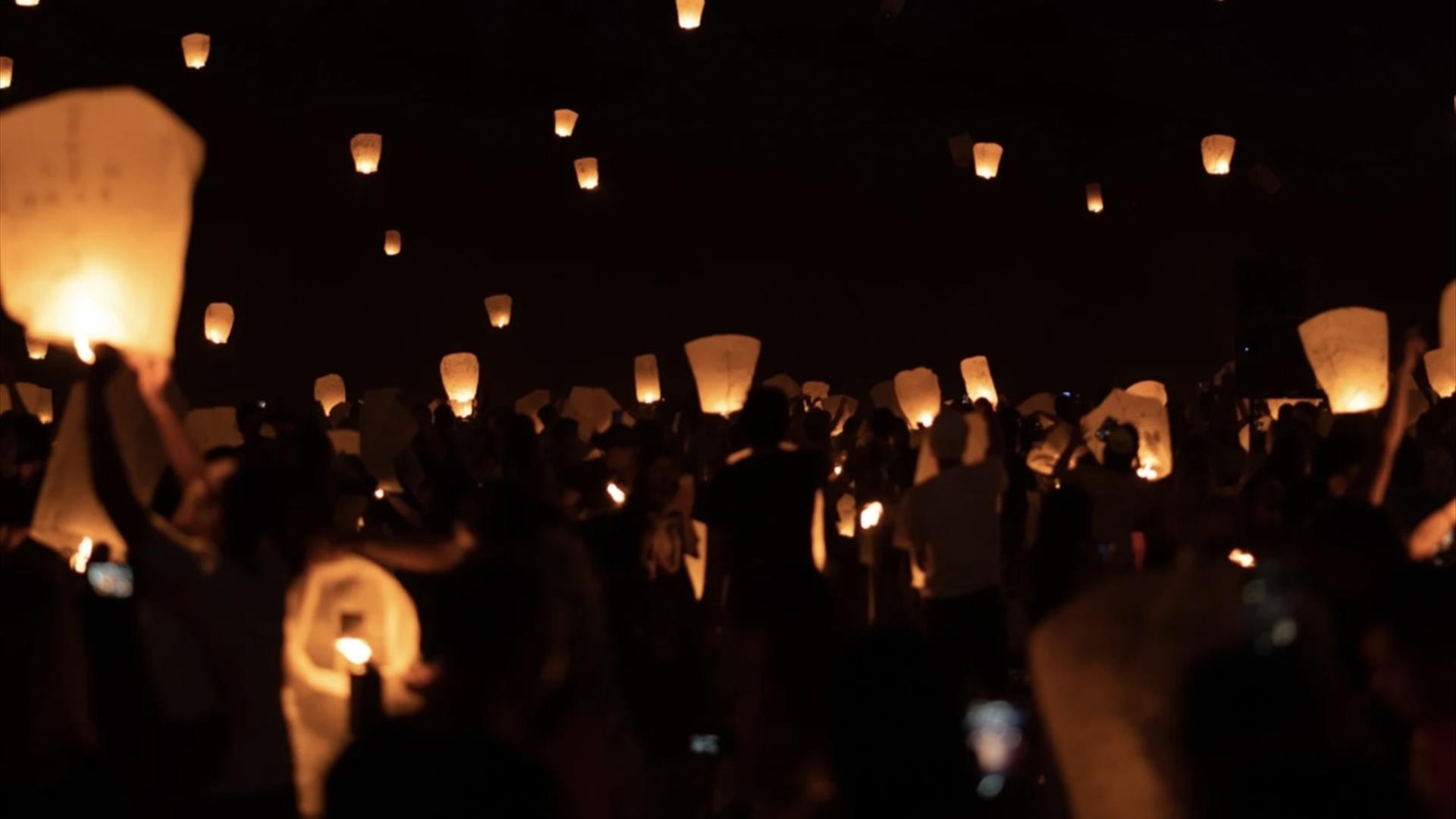 Photograph of floating halloween willow lanterns in the sky at night.