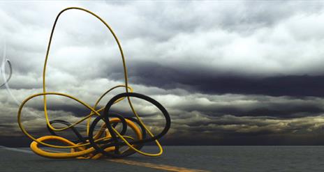 Grey cloudy stormy sky with hint of yellow sunset in the background. There are two pipes: yellow and black which are interweaved in the foreground.