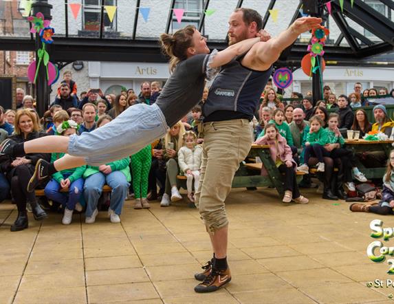 Promotional image for the traditional Irish music and dancing happening in the Craft Village, showing two people dancing while an audience watches.
