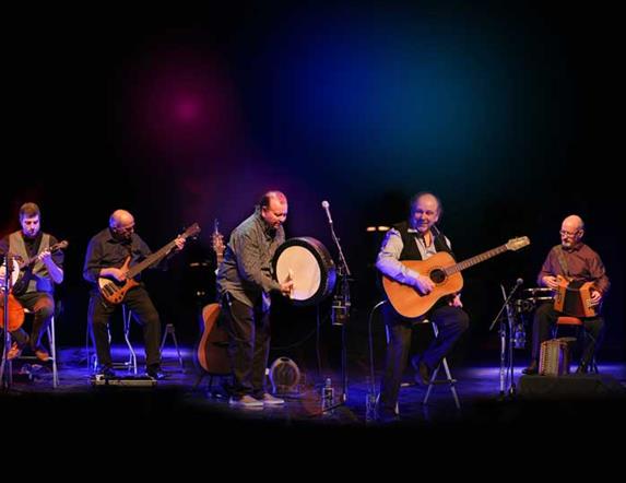 The Fureys against a black background, playing their instruments enthusiastically.