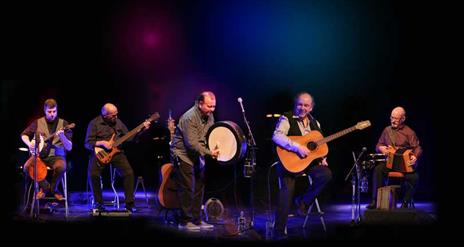 The Fureys against a black background, playing their instruments enthusiastically.