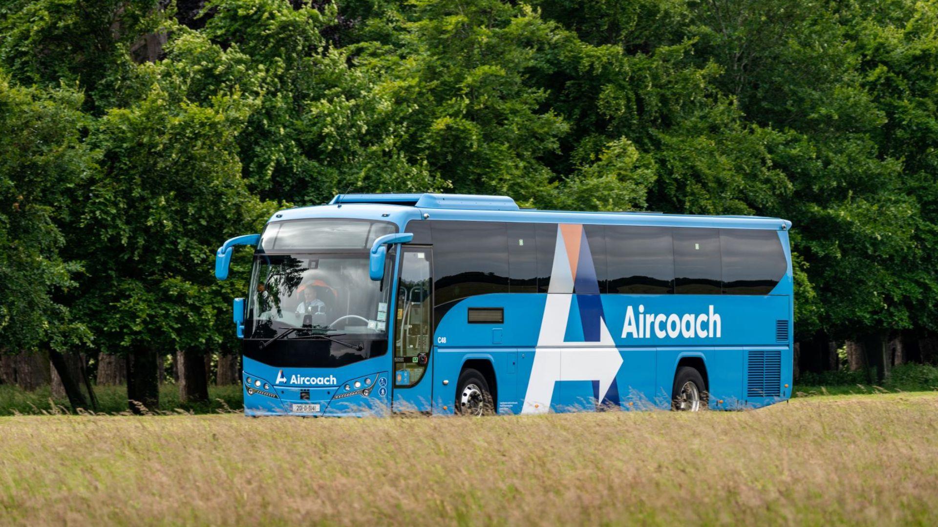 Image of blue bus driving past trees