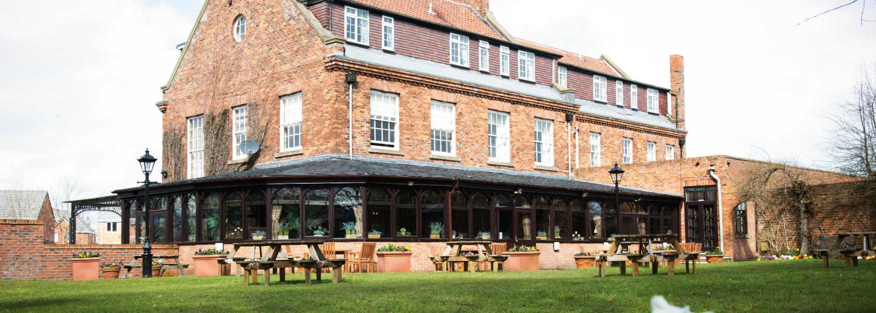 View of exterior of a building with conservatory and spring flowers on display