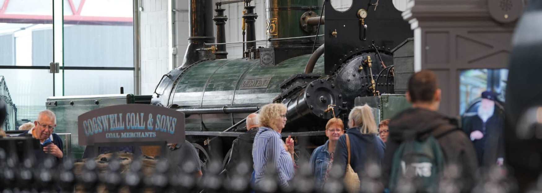 A group of visitors looking at a steam engine train