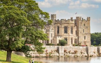 Two people walking in front of Raby Castle and lake