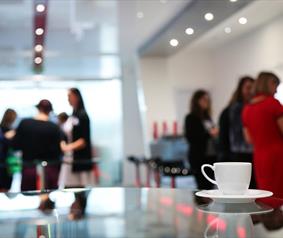 A cup of tea on a table with a conference group in the background