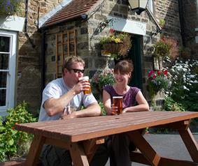 couple enjoying a drink outside a countryside pub.