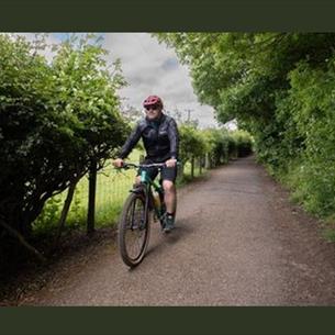 A man riding a bike along a single track road in the countryside