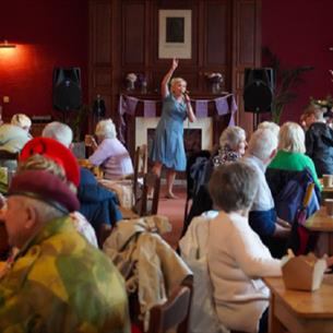 A crowd sitting at tables enjoying a 1940s musical entertainer.