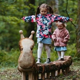 Two children playing on wooden sculpture.