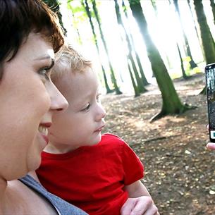 Woman with child looking at App on a mobile phone, forest setting