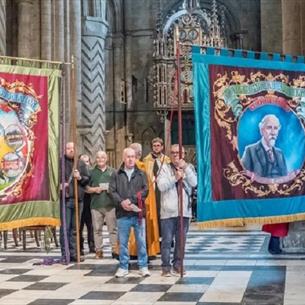 A group of people displaying Miners Banners in Durham Cathedral