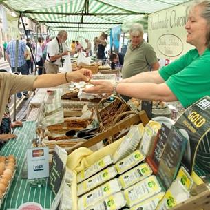 Trader at Barnard Castle Farmer's Market at stall taking money from customer