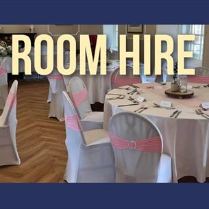 Dining room set up with round tables.  White table and chairs coverings - chairs with a pink sash.