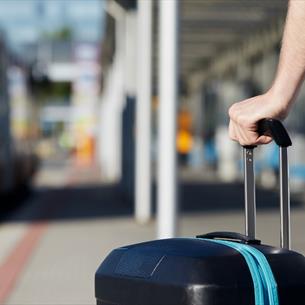 A person holding a suitcase in a bus station