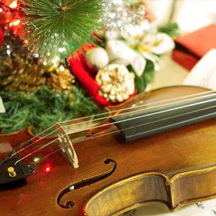 A violin and sheet music with Christmas decorations