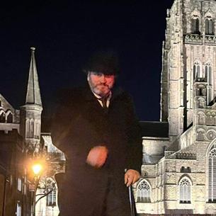 Andrew Ross (Tour guide) standing n front of Durham Cathedral on a dark evening