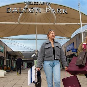 Shoppers leaving Dalton Park Outlet and Outdoors with lots of bags, smiling. 